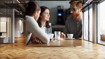 Diverse friends meeting in coffeeshop talking at table, happy students have fun in cafe enjoying coffee spending time together, millennial work mates or colleagues hang out in cafeteria during break Wall mural