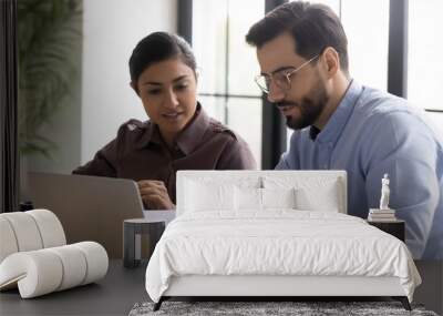 Diverse smiling businessman and businesswoman reading finance report talking looking at document. Indian woman and male manager discuss and looking decision in negotiation. Teamwork at workplace. Wall mural