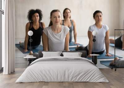 Diverse women doing cobra exercise at group lesson, practicing yoga Wall mural