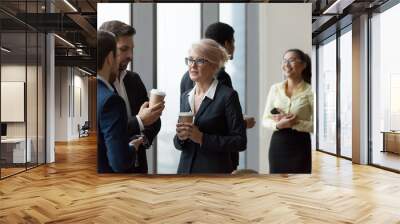 Diverse workers having conversation standing in office at work break Wall mural