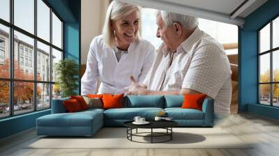 Elderly man patient and middle-aged nurse talking indoors Wall mural