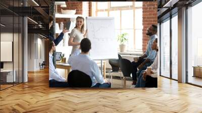 Employee asking questions to confident smiling female business coach, speaker, multiracial colleagues group at meeting, talking about growth of sales graph, good result, training team of office Wall mural