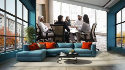 European business leader woman holding meeting with Arab partners. Multiethnic group of stakeholders, board of directors sitting at large table, talking, smiling, laughing, discussing teamwork Wall mural