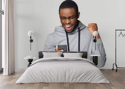 Excited black man feel overjoyed reading good news on cellphone Wall mural