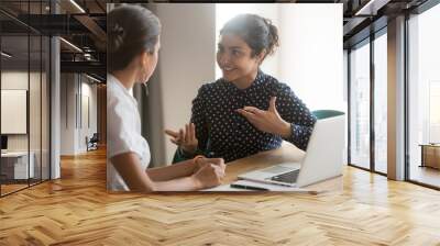 Excited diverse female colleagues discuss ideas at workplace Wall mural