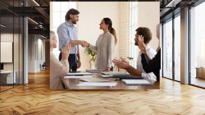 Executive shaking successful happy businesswoman hand at meeting, smiling team leader greeting new employee or thanking for good work result, colleagues applauding congratulating with promotion Wall mural