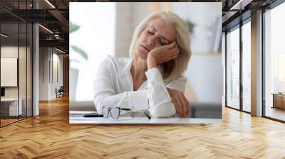 Exhausted senior businesswoman fall asleep at workplace Wall mural