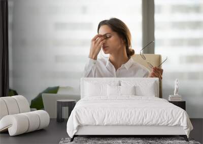 Fatigued businesswoman taking off glasses tired of computer work, exhausted employee suffering from blurry vision symptoms after long laptop use, overworked woman feels eye strain tension problem Wall mural