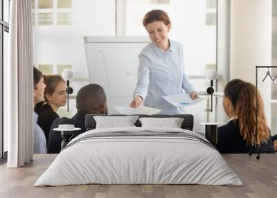 Female manager giving paper report to diverse employees at meeting Wall mural