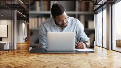 Focused african business man make notes study work on laptop Wall mural