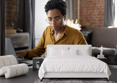 Focused millennial Black business woman calculating finance, money, using calculator, laptop computer at home workplace table, counting budget, paying bills, taxes, rent, mortgage fees Wall mural