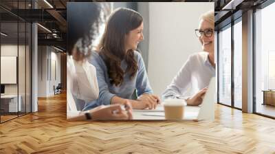 Friendly smiling old and young businesswomen talking laughing at meeting Wall mural