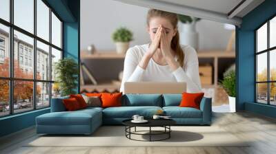 Frustrated sad millennial young woman sitting at the office desk or home. Covering face with hand female worker feels unhealthy headache or eyestrain. Student has a problems receive bad news concept Wall mural