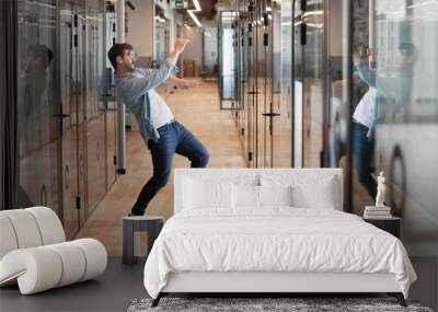 Funny millennial male dancing in hallway celebrating success Wall mural