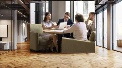 Group of successful business partners meeting at table in office lobby, cafe, talking, discussing common project, investment, startup, agreement, partnership, cooperating on deal Wall mural