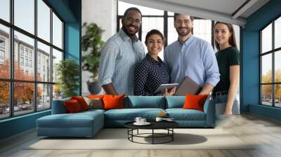 Group portrait of happy multiethnic united millennial team in modern office. Successful employees standing together, meeting in workspace, looking at camera and smiling Team work concept. Head shot Wall mural