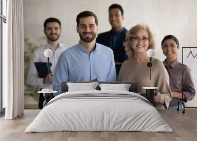 Group portrait of smiling diverse multiethnic businesspeople pose together in office, happy multiracial colleagues coworkers feel motivated successful show team strength and unity, leadership concept Wall mural