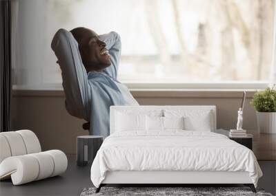 Happy african American man relaxing in chair at workplace Wall mural