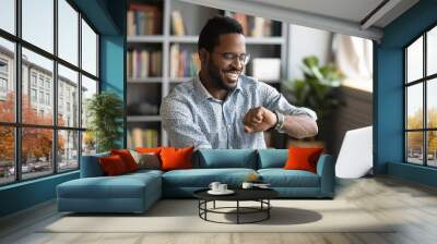 Happy african businessman worker looking at smart watch at work Wall mural