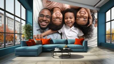 Happy african family lying on bed cuddling, portrait, top view Wall mural