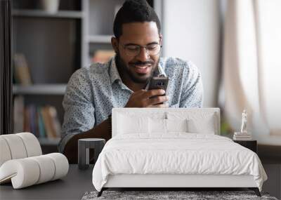 Happy african man using smartphone sit at home office desk Wall mural