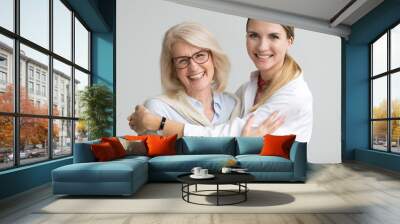 Happy attractive senior older aged mother and young adult daughter smiling laughing looking at camera, two beautiful women having fun embracing head shot portrait, cheerful family hugging concept Wall mural