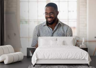 Happy black businessman holding smartphone using apps standing in office Wall mural