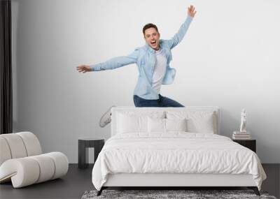 Happy cheerful young man jumping feeling joy isolated on background Wall mural