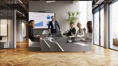 Happy different aged business team having fun on office meeting, talking, laughing, brainstorming at conference table. Positive confident male speaker, presenter giving statistic report to group Wall mural