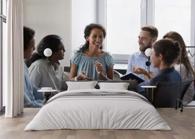 Happy diverse addicts sitting on chairs in circle, talking on group therapy meeting, discussing addiction, mental health problems. Multiethnic employees brainstorming on team training Wall mural