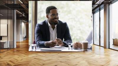 Happy diverse different aged business team discussing work. Leader and employees talking in office meeting room together, brainstorming, sharing ideas and solutions, negotiating on project. Wall mural