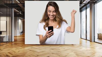 Happy excited woman celebrating success, looking at phone screen Wall mural