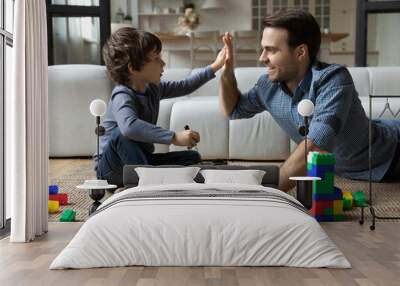 Happy father and little son giving high five, repairing toy car with screwdriver, playing on floor in living room at home, happy dad and adorable child boy having fun, spending leisure time together Wall mural