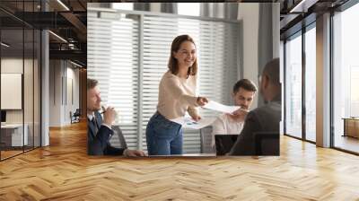 Happy female boss giving paper financial report to employees clients Wall mural