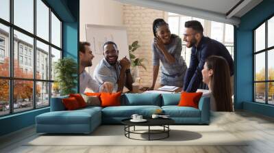 Happy friendly multiracial team laughing working together at corporate briefing Wall mural