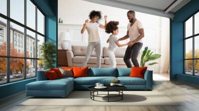 Happy funny active african family with daughter dancing at home Wall mural