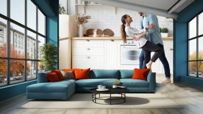 Happy loving young couple dancing romantic dance on date in modern kitchen, smiling husband and wife celebrating anniversary, enjoying tender moment, having fun, moving to music at home Wall mural