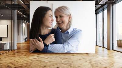 Happy mature mother hug cuddle grown-up beautiful daughter enjoy spending time together, smiling senior mom embrace adult girl child show love and care, family good relationships concept Wall mural