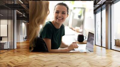 Happy millennial intern, student girl talking to teacher, consulting tutor, mentor at computer in training center, discussing new professional skills, smiling, laughing. Business education, internship Wall mural