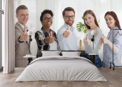 Happy millennial multiracial people standing together showing thumbs up sign, smiling young employees or workers make gesture recommending good service, diverse colleagues give recommendation Wall mural