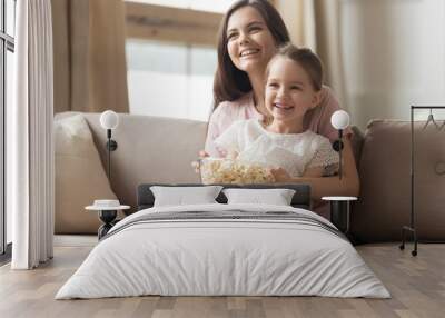 Happy mom and child girl laughing watching tv on sofa Wall mural