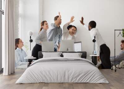 Happy multi-ethnic employees sales team giving high five together celebrating corporate success and good relations, diverse group of office people joining hands excited by common victory achievement Wall mural