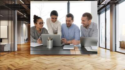 Happy multiethnic businesspeople look at laptop screen discuss company startup project at meeting together, smiling multiracial employees brainstorm work on computer at briefing, teamwork concept Wall mural