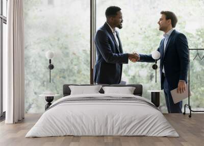 Happy multiracial male business partners shake hands get acquainted greeting at office meeting, smiling diverse businessmen handshake closing deal after successful negotiation, partnership concept Wall mural