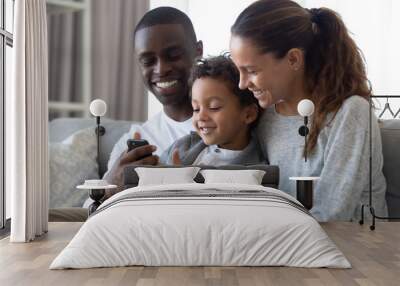 Happy multiracial parents with son using cellphone at home Wall mural