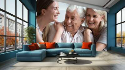 Happy older parents father and mother with adult daughter hugging close up, laughing at joke, chatting, sharing news, young granddaughter and mature grandparents having fun, spending weekend together Wall mural