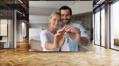 Happy proud millennial couple holding, showing keys, smiling at camera. Husband and wife, new homeowners, tenants excited with buying house, real estate property purchase, renting apartment. Close up Wall mural