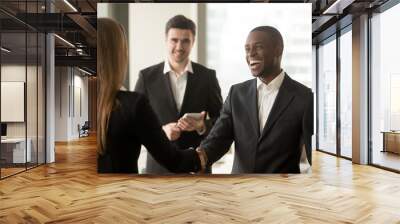 Happy smiling afro american businessman and caucasian businesswoman shaking hands standing in modern office, nice to meet you, first impression, congrats, promoted to the post, reward accomplishments Wall mural