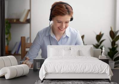 Happy smiling businesswoman in headphones self-study at office desk Wall mural