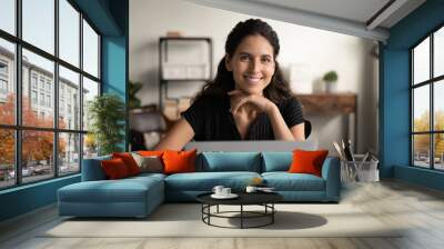 Happy worker. Headshot portrait of confident young latin female posing by office computer at work desk. Smiling successful millennial woman remote employee freelancer sit at workplace look at camera Wall mural